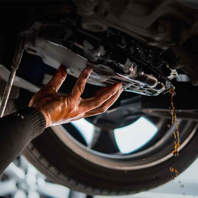 Car mechanic draining the old automatic transmission fluid during an oil change service